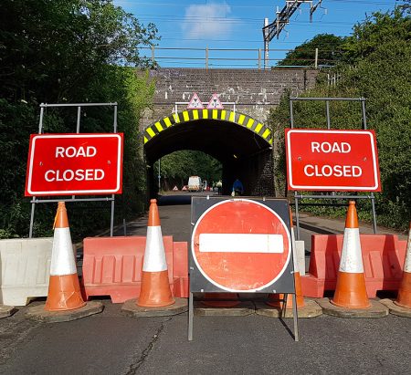 Photo of 'road closed' signs and barrier at the railway bridge in June 2019.