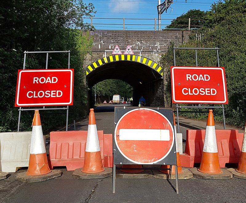 Photo of 'road closed' signs and barrier at the railway bridge in June 2019.