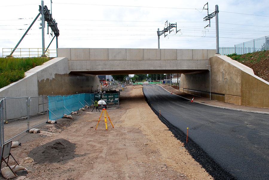 Photo of a partly-tarmacked road under a bridge.