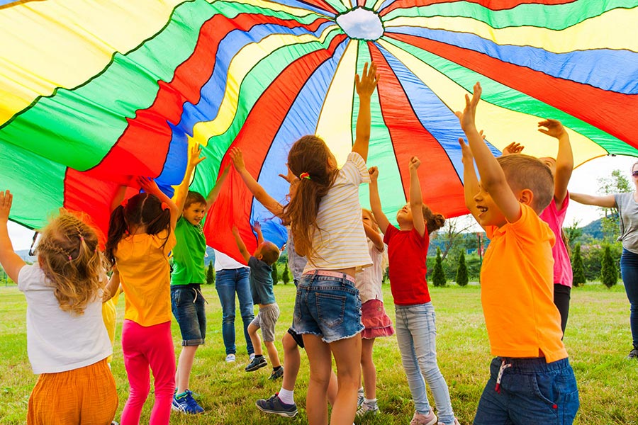 Photo of children playing under a colourful parachute.