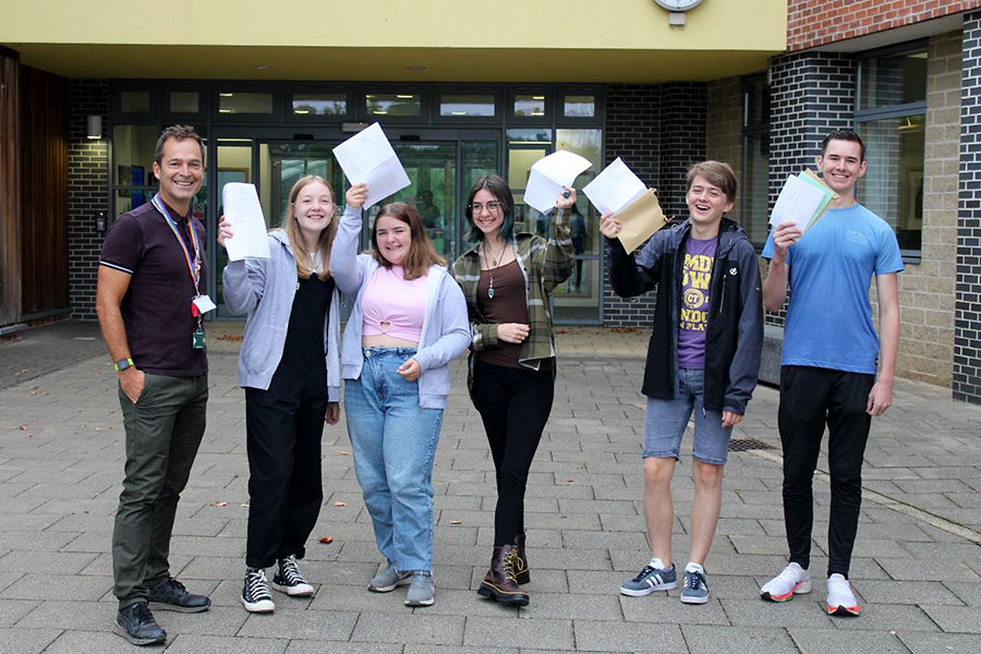 Photo of a group of students holding envelopes and papers., along with one other person.