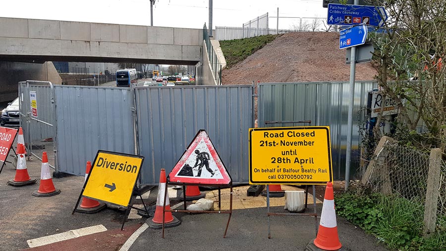 Photo of road signage at a works site near a railway bridge.