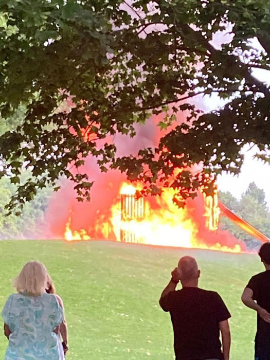 Photo of people watching a large play fort going up in flames.