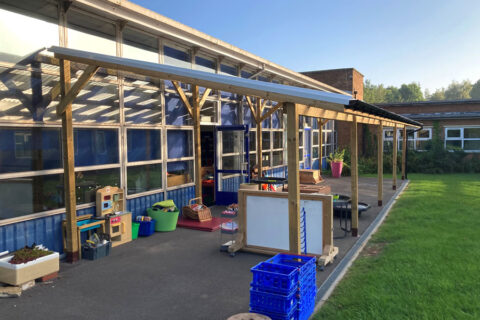 Photo of a covered lean-to area along the side of a school building.